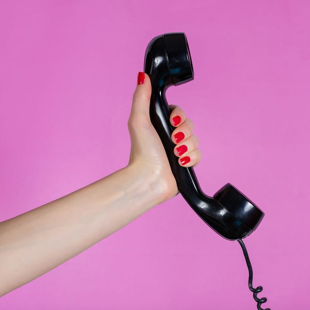 female hand holding old and retro telephone headset isolated on pink background in studio