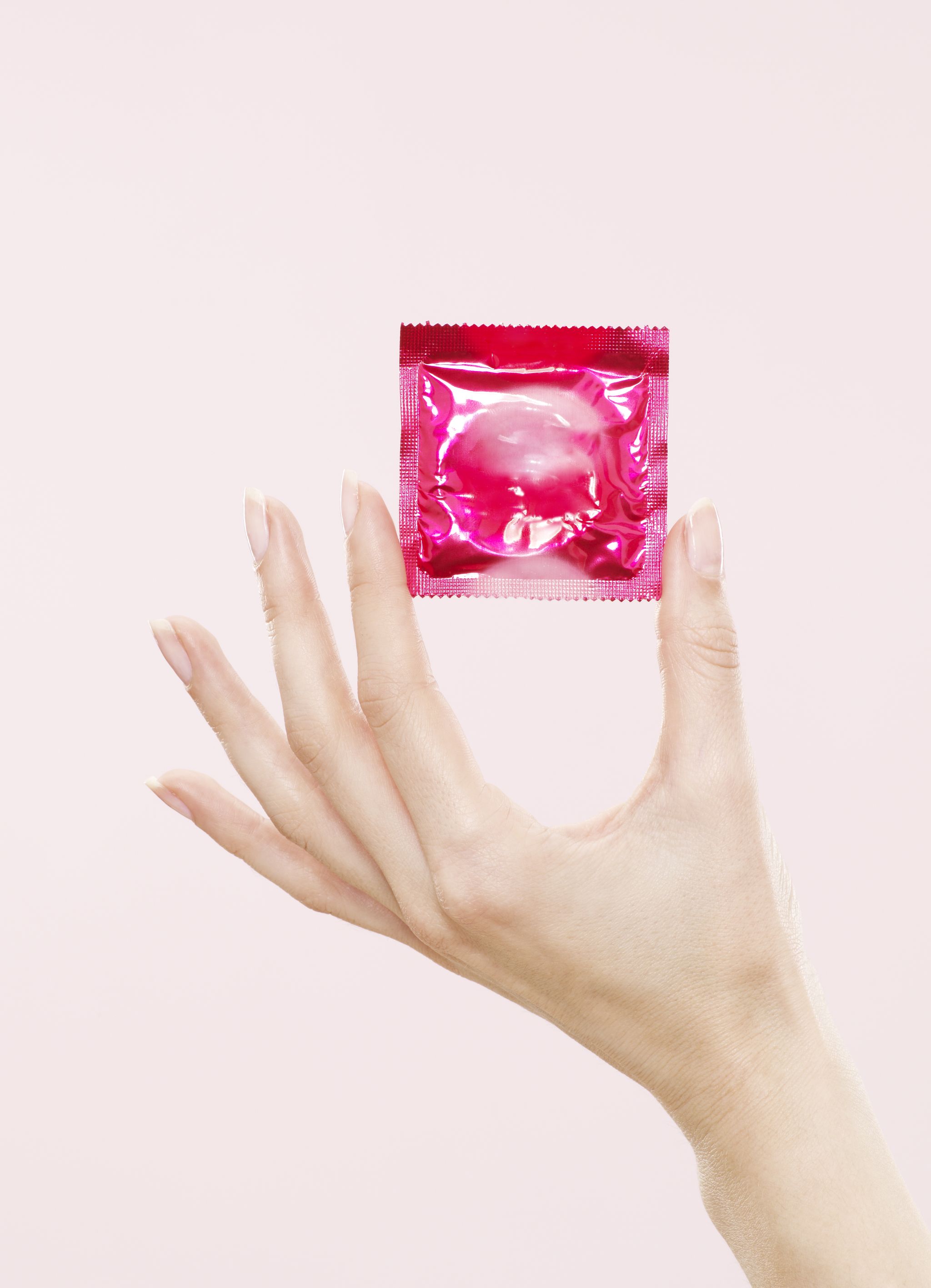 female hand holding sealed condom packet