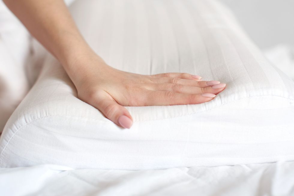 female hands hold and show an orthopedic pillow on a white bed comfortable sleep and healthy spine