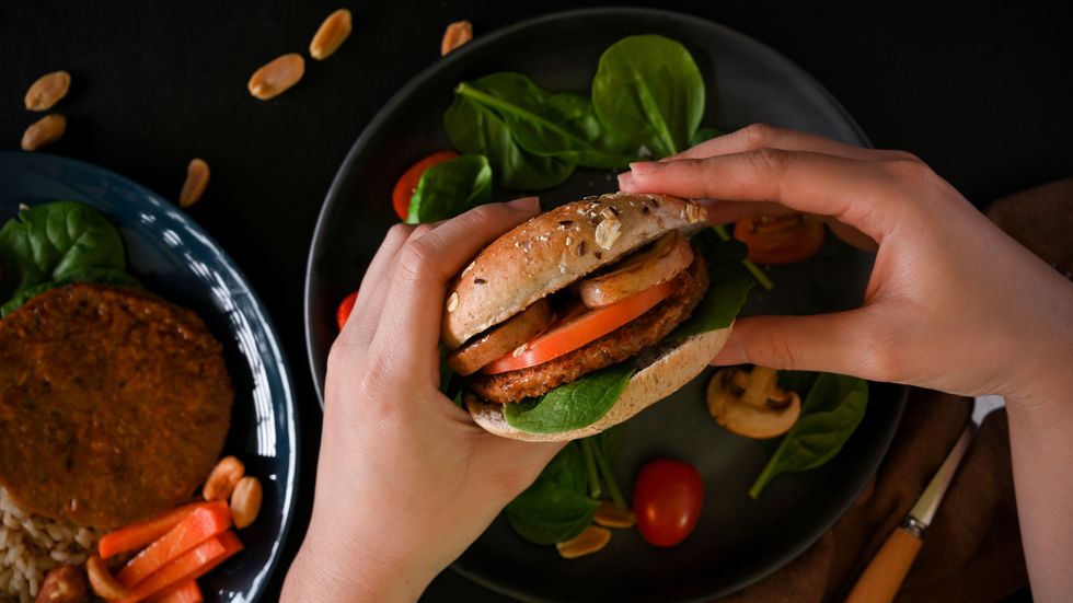 female hands holding tasty plant based meatless burger with vegetable sliced