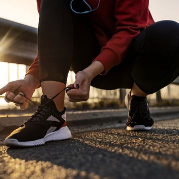 female hands lacing running shoes ,morning sun in background