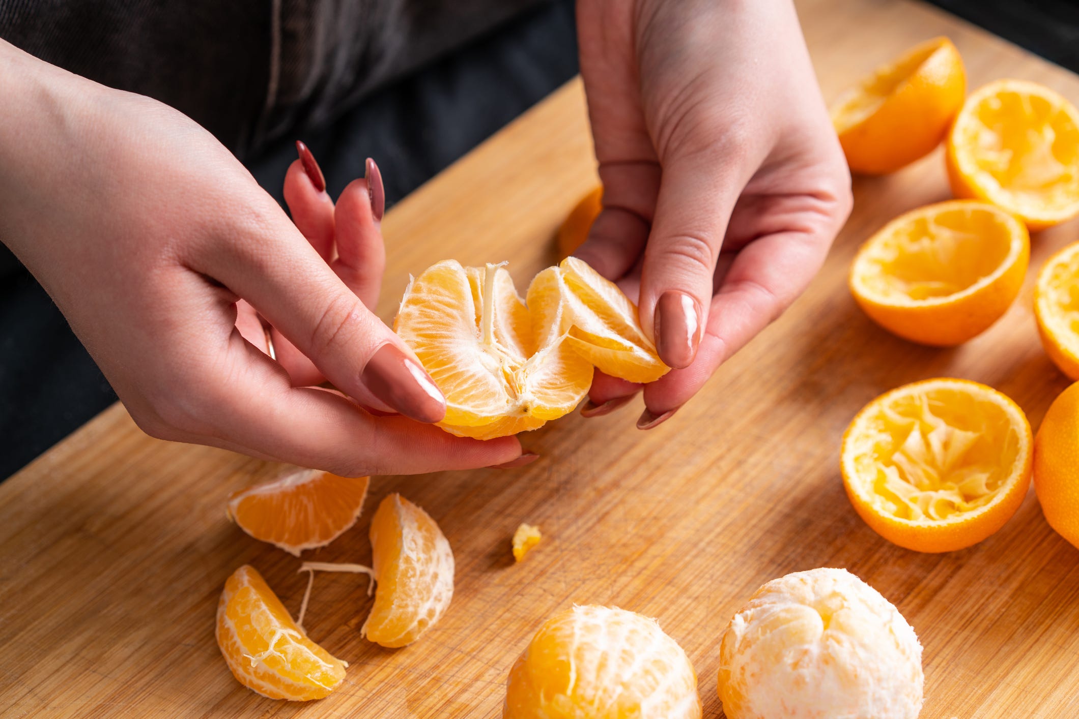 female hands peel and break ripe tangerine, homemade juice preparation
