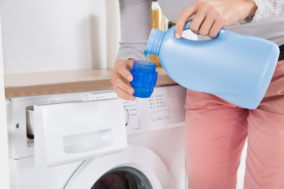 female hands pouring detergent in the bottle cap