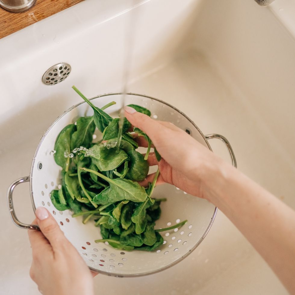 female hands washing spinach vegetables at the kitchen sink