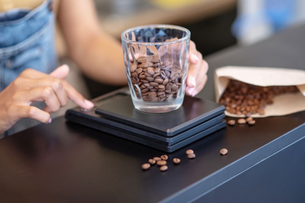 female hands weighing coffee beans in glass