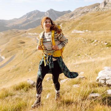 female hiker with colorful backpack feeling freedom among majestic mountains.