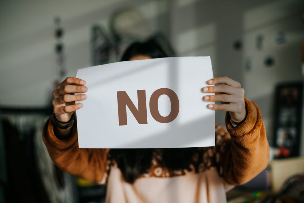 female holding paper with word no written