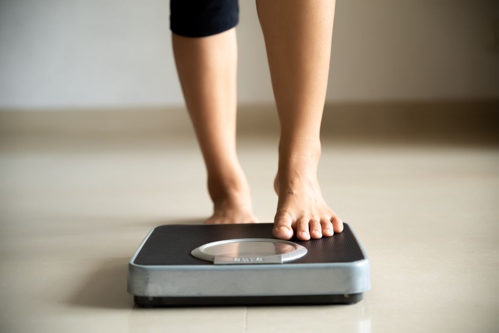 female leg stepping on weigh scales healthy lifestyle, food and sport concept