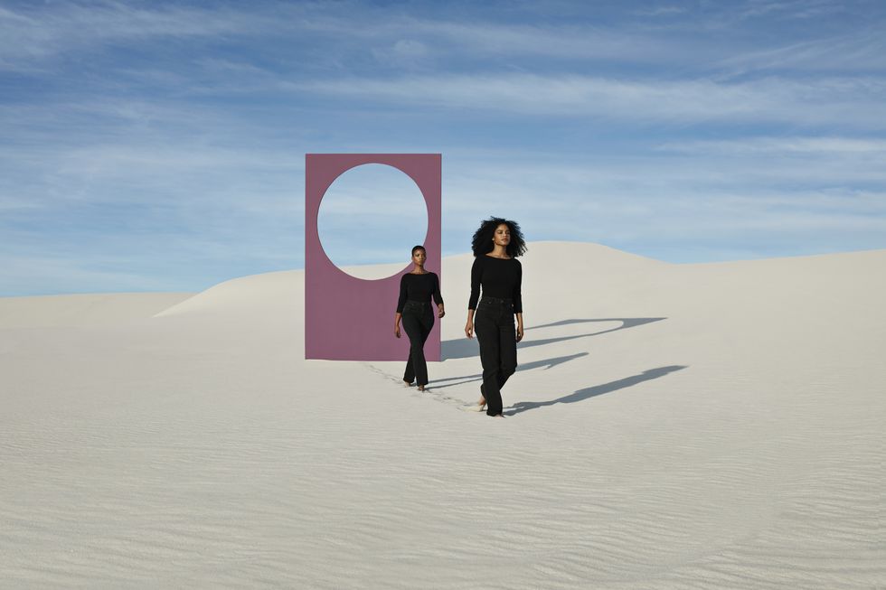 female models walking on white sand dunes against portal at desert