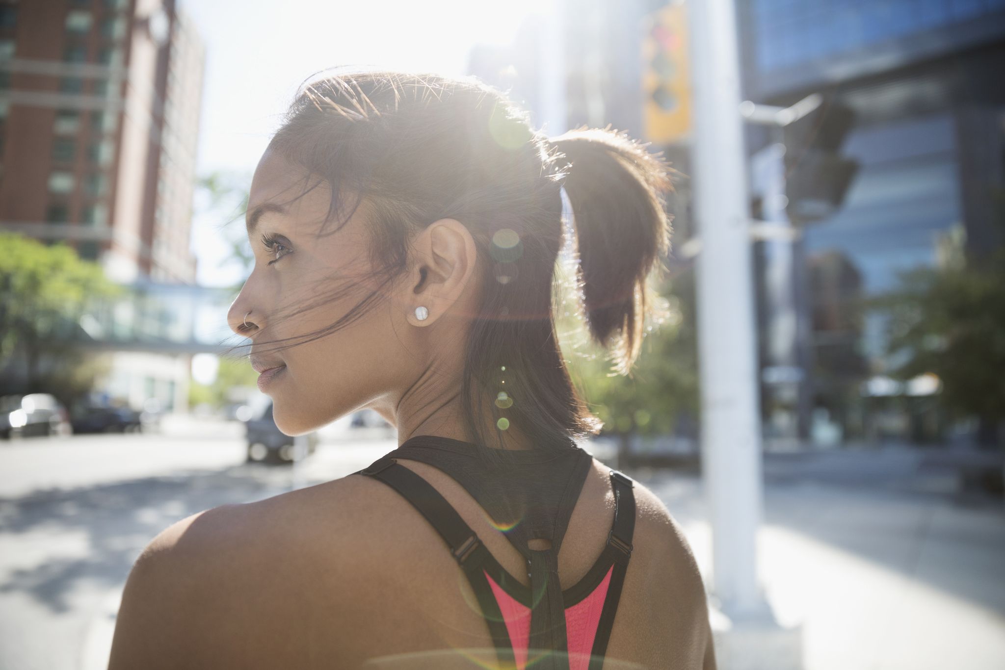 Female runner looking away on sunny urban street
