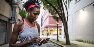 female runner using mobile device in urban area