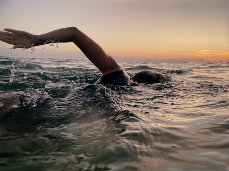female sea swimmer at sunset