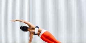 female sportswoman doing side plank pose in front of wall