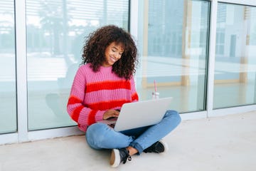 female student using laptop sitting on the floor