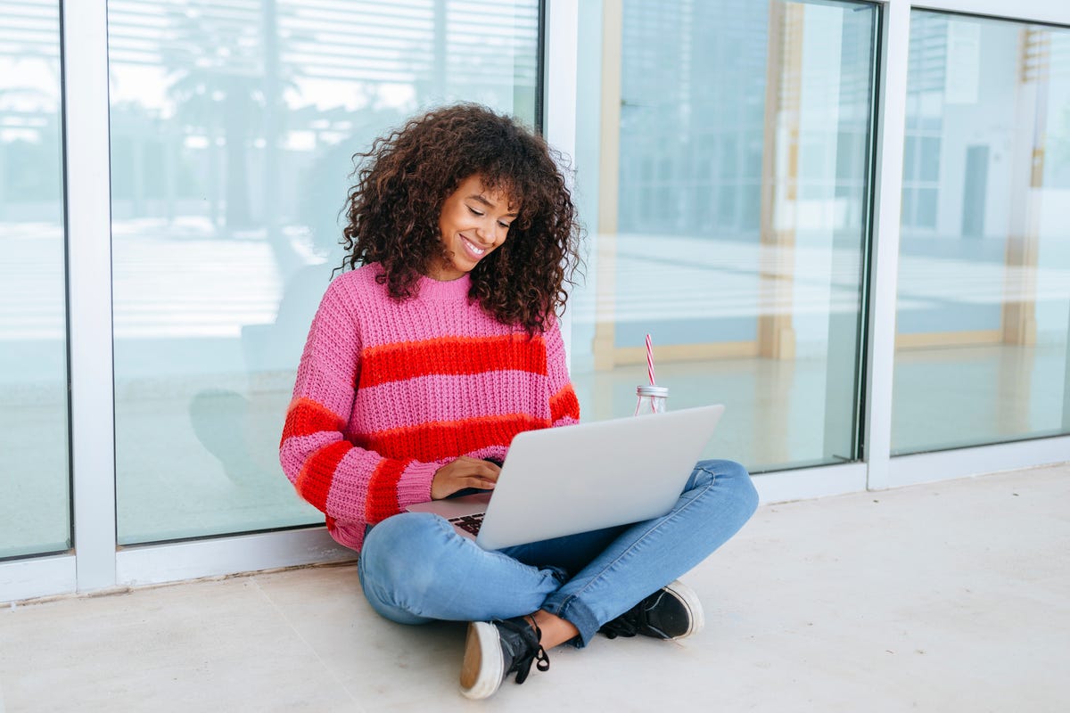female student using laptop sitting on the floor