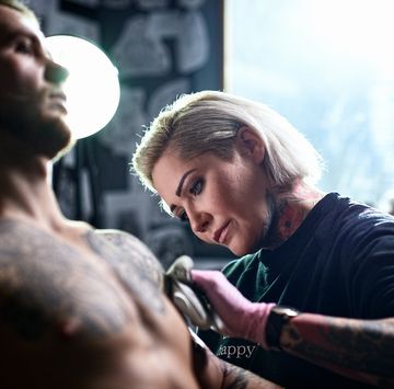 female tattooist applying tattoo to male customer