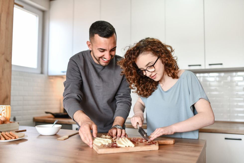 female teaching boyfriend how to serve and prepare food at home