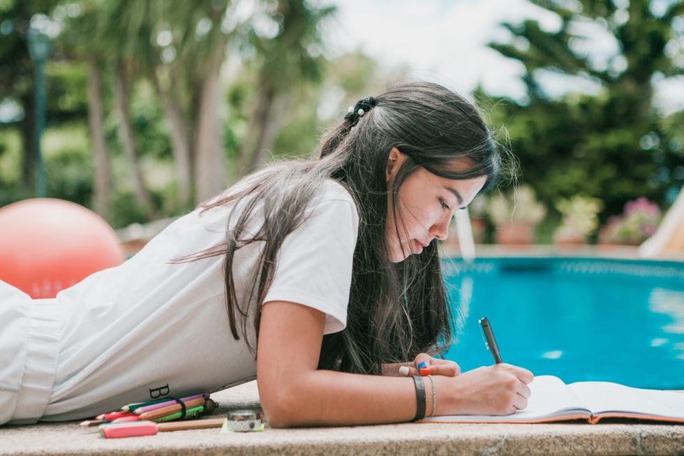 female teenager doing homeworks in back yard in a sunny day