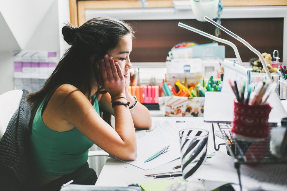 female teenager feeling stressed studing at homee learninghome schooling