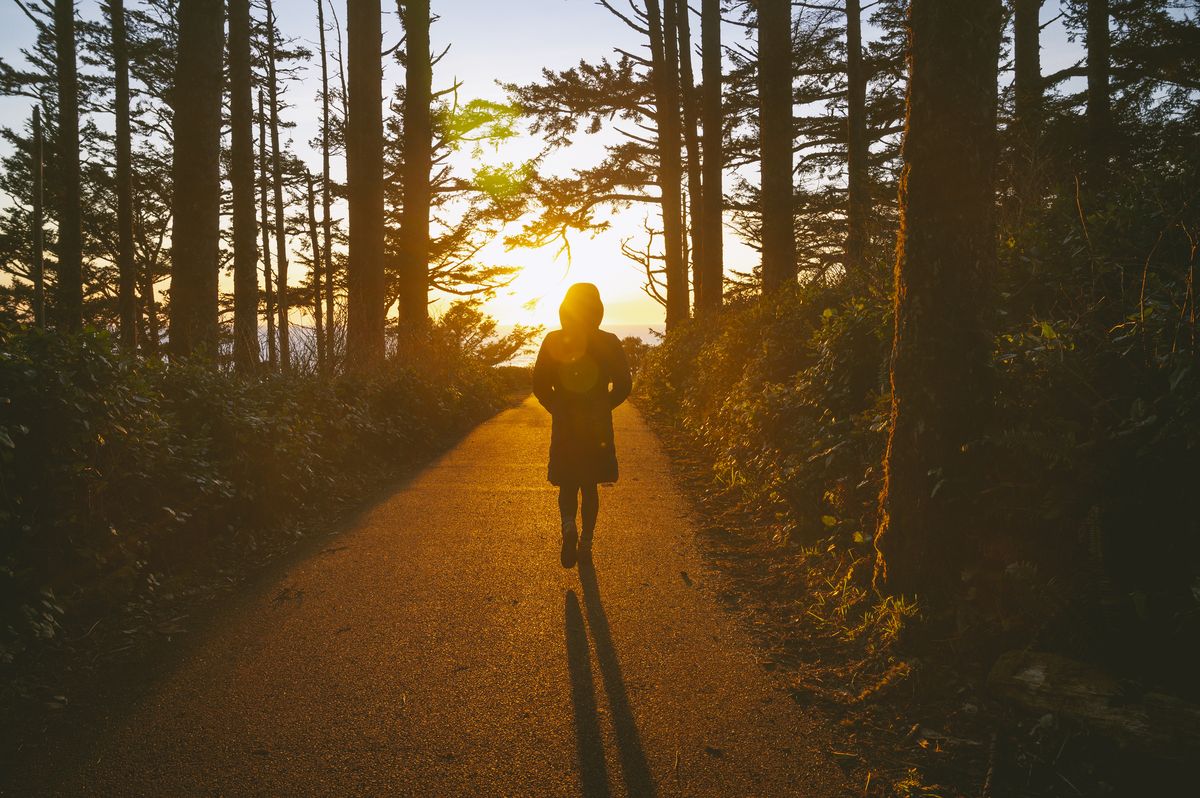 female walking on a path into the sunset at cape disappointment