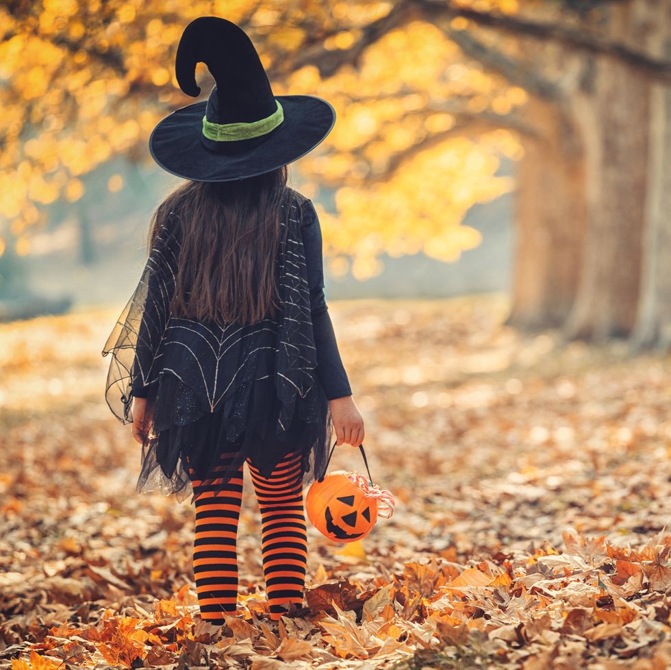 little girl in witch costume having fun outdoors on halloween trick or treat