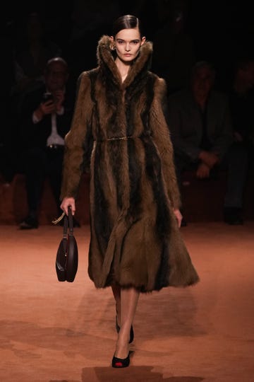 Fashion model showcasing a luxurious fur coat and handbag