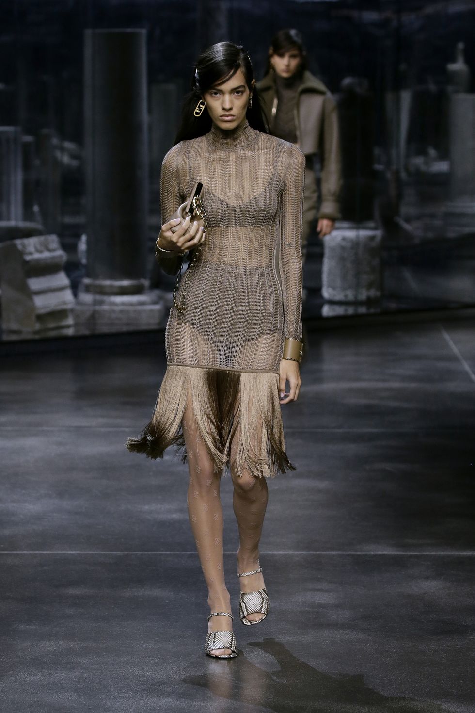 modelo desfilando para fendi con vestido semitransparente con flecos en el bajo y sandalias de pitón