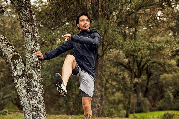 fernando carro hace un ejercicio junto a un árbol en una sesión fotográfica para la revista runner's world