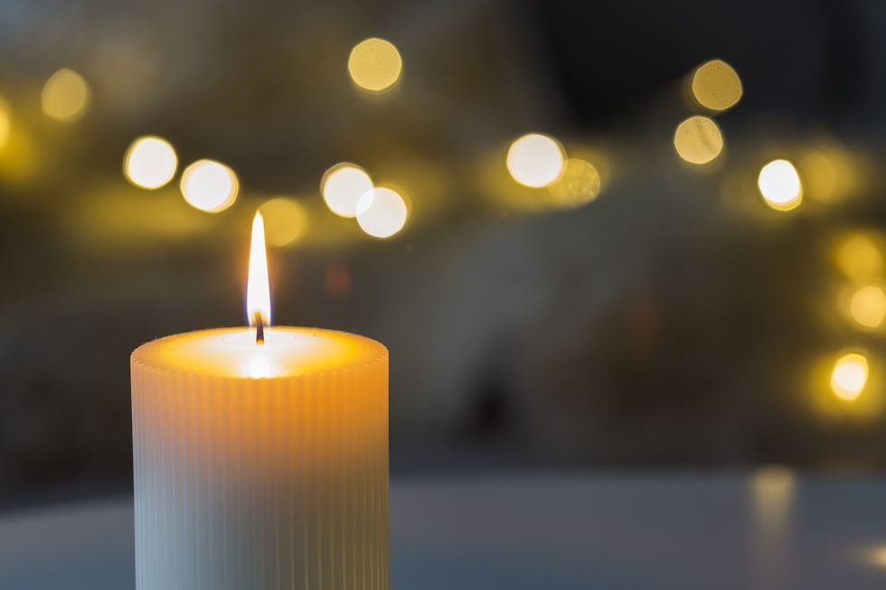 festive background with burning candle and bokeh