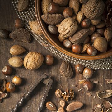 Festive bowl of mixed whole nuts in shells in a wooden bowl on a gold placemat