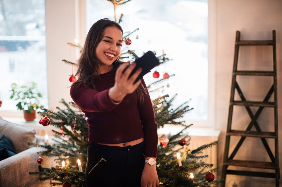 woman taking a selfie in front of a christmas tree