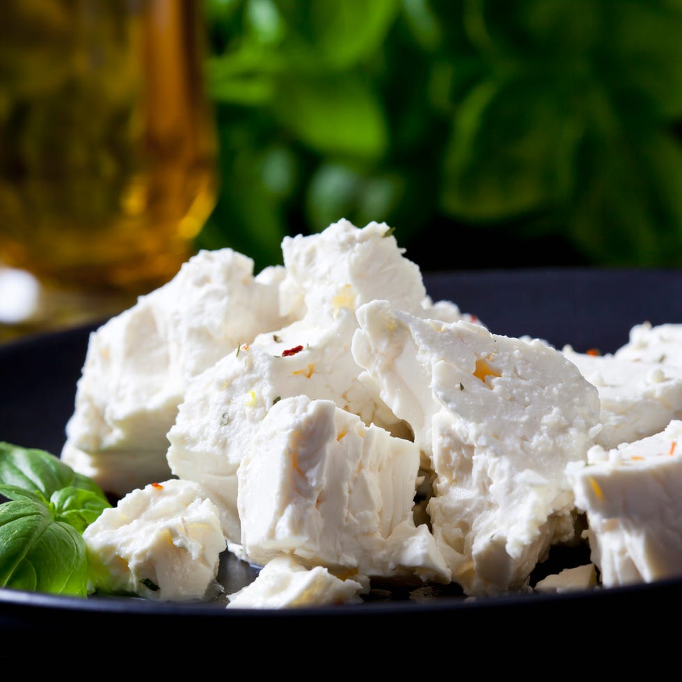 Feta, herbes and basil leaves on black plate, close-up feta, herbes and basil leaves on black plate,