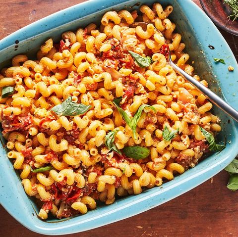 baked feta macaroni with tomatoes and basil in a blue baking dish