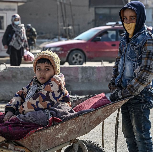 an afghan boy pushes a wheelbarrow as the other sits on it along a street in kabul on january 14, 2022 photo by mohd rasfan  afp photo by mohd rasfanafp via getty images