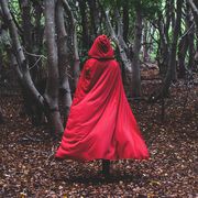 Figure in red cape going through forest