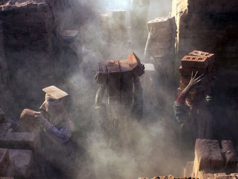 In India zijn deze vrouwen die in een stenen oven werken bedekt met stof Aangezien de urbanisatie in India voor meer gebouwen zorgt is de vraag naar bakstenen hoog Werknemers worden vaak geconfronteerd met trieste omstandigheden werkdagen van achttien uur en een laag inkomen