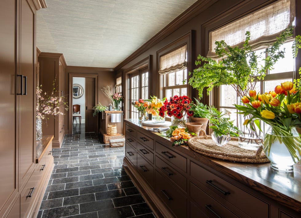 a kitchen with a countertop full of flowers in various containers and a gray tile floor