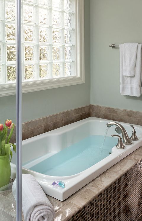 filled soaking tub next to glass shower