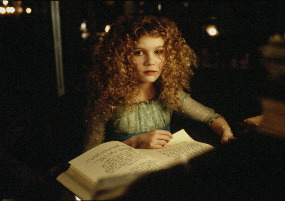 kirsten dunst looking up as she flips through pages of a book during a movie scene