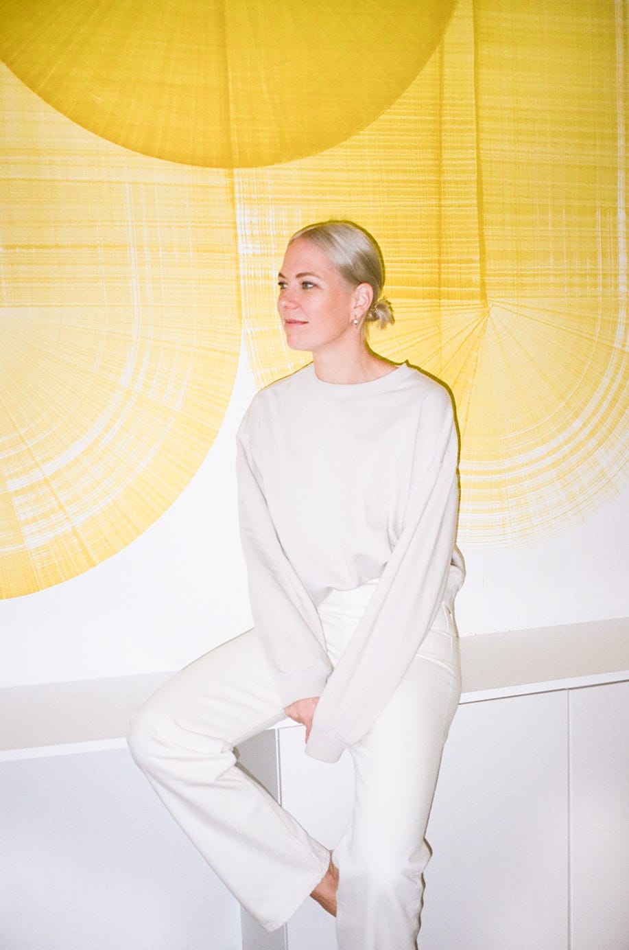 stylish individual seated against a vibrant yellow backdrop