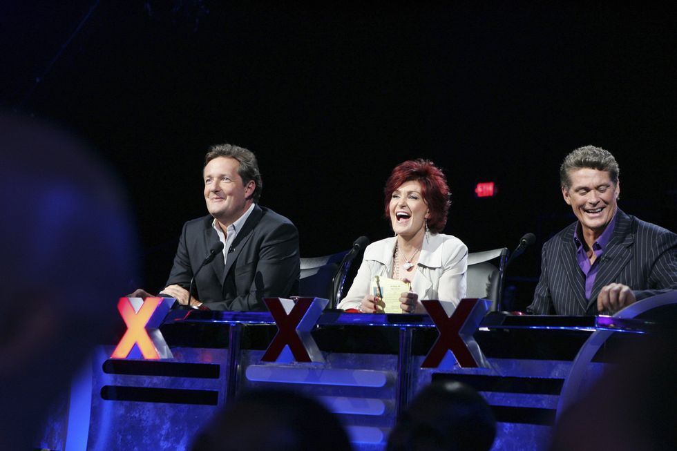 two men sit on either side of a woman behind a desk, all three smile as they look at very places