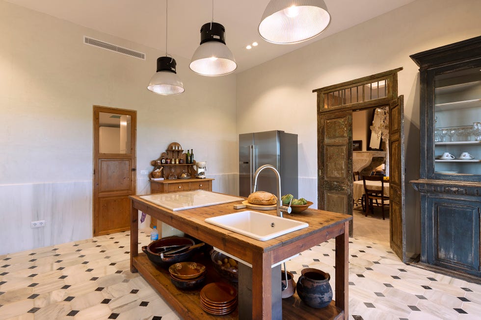 Mesa de madera antigua a modo de isla central de la cocina