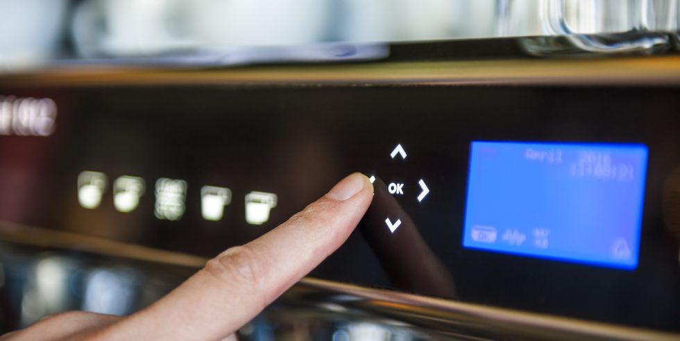 finger pushing digital button on coffee machine