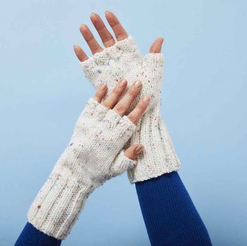 hands wearing cream fingerless gloves against blue background