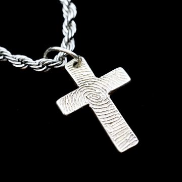 fingerprint markings on a memory necklace shaped as a cross