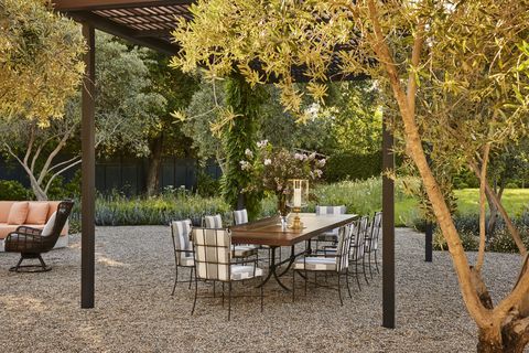 striped cushions outfit the seating around a custom iron and teak dining table that is shaded