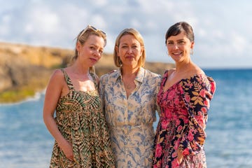 three women standing together on a beach