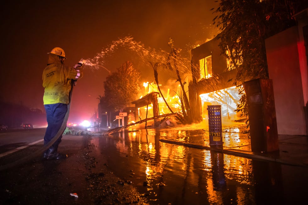 firefighter extinguishing flames consuming a building during california wild fires