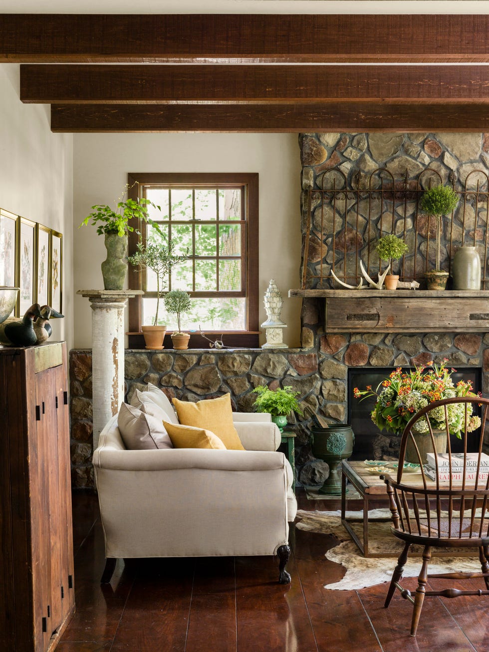 living room with a fieldstone wall and fireplace with a hunky wood mantel