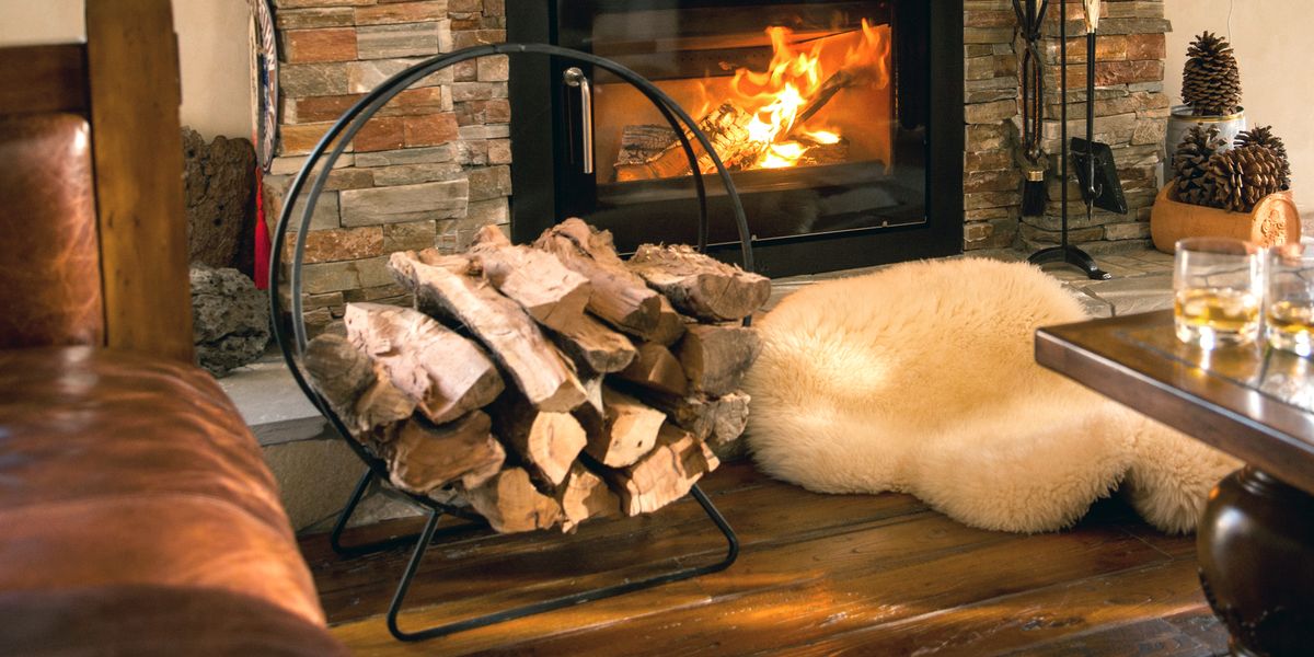 circular iron firewood rack in front of fireplace with sheepskin rug and pinecones